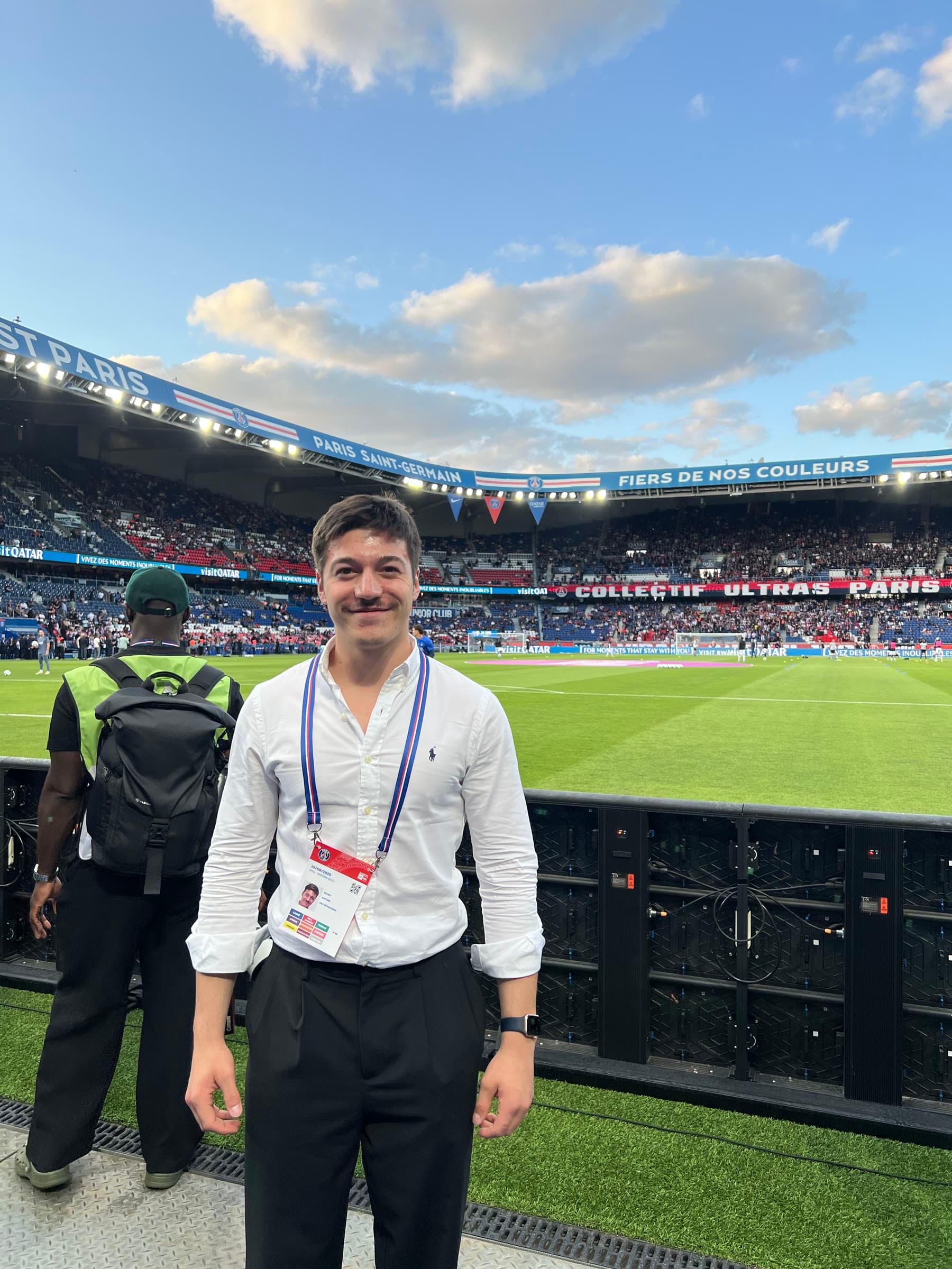 Pitchside at the Parc des Princes before kick-off, accreditation around the neck, the stands filling up behind.