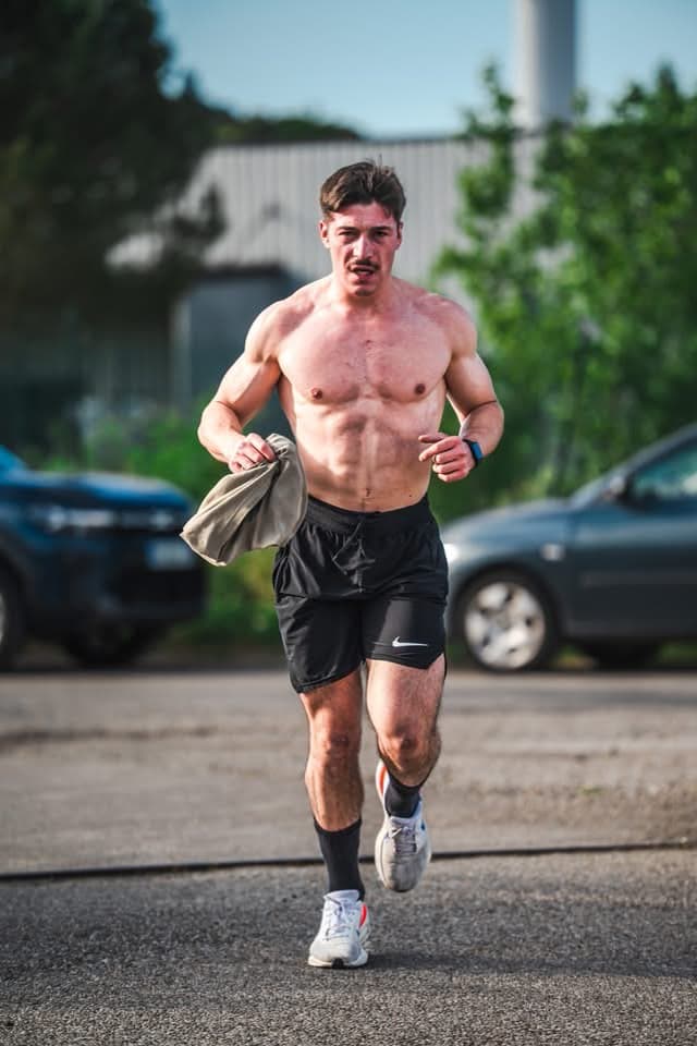 Running flat out on an empty road in the early morning, shirt in hand.